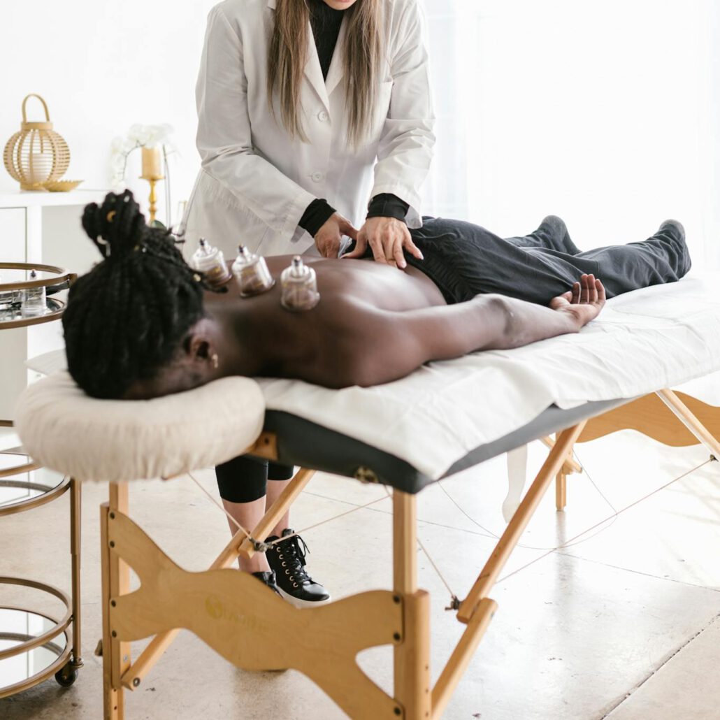 A therapist conducts cupping therapy on a man lying on a massage table, promoting wellness.